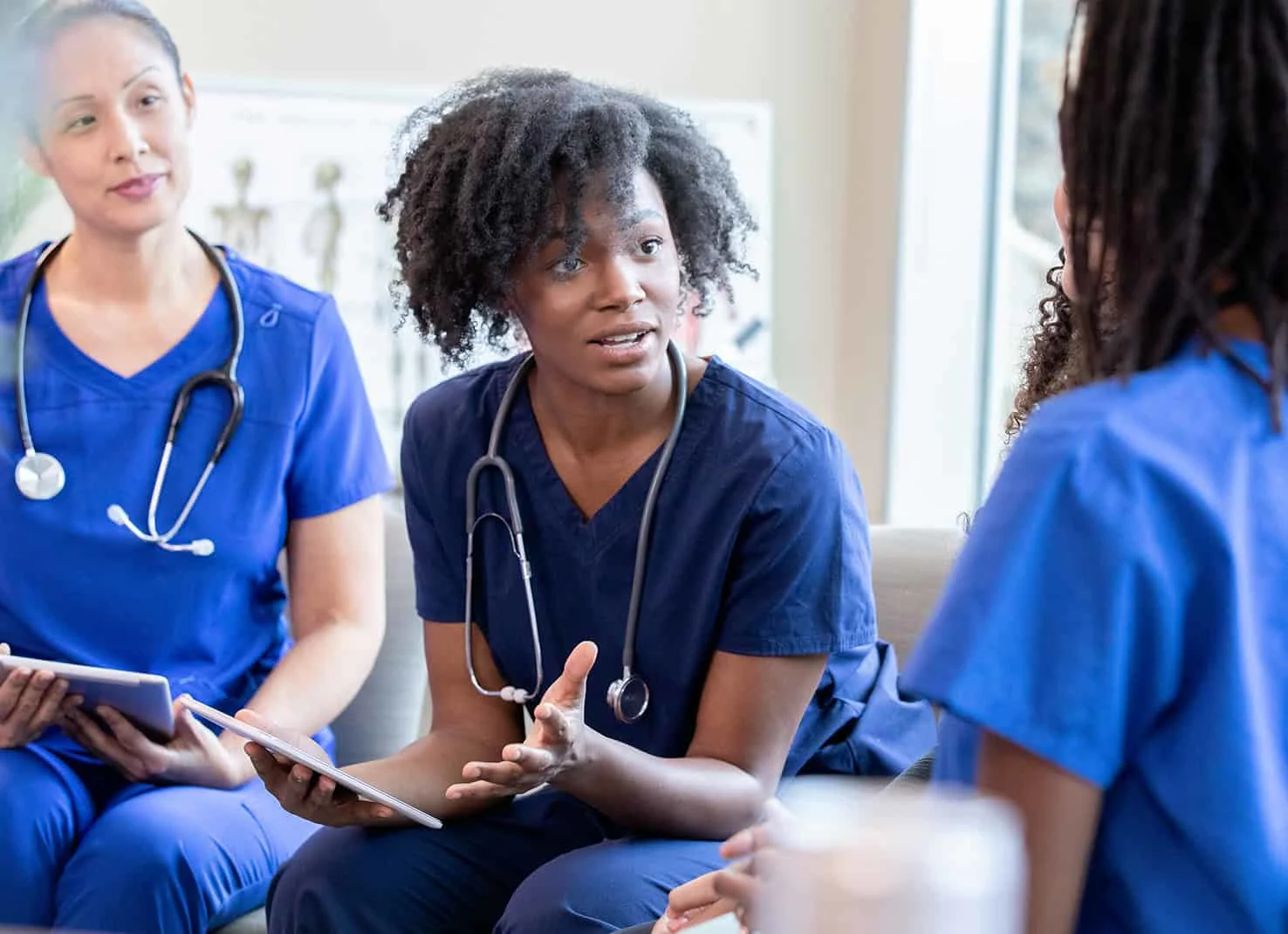 Group of health professionals have discussion while holding tablets