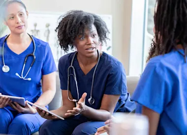 Group of health professionals have discussion while holding tablets