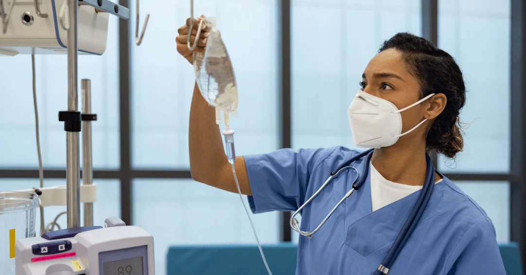 A female nurse hanging up an IV bag in a hospital room