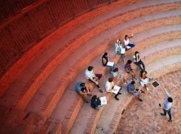 An outdoor lecture at a university with students raising hands
