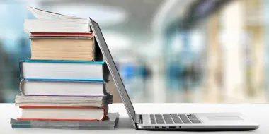 A stack of books next to laptop