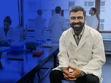 Global South researcher sitting in lab with colleagues
