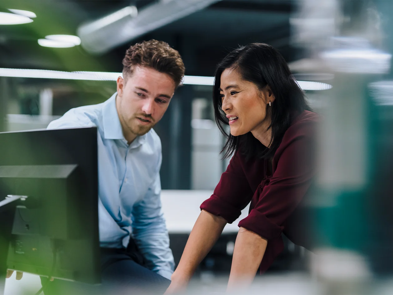 Two workers examining findings on a desktop screen.