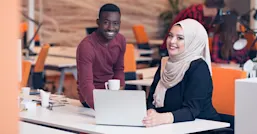Two people working on laptop in an office