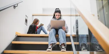 女学生在楼梯间使用笔记本电脑。（©istock.com/iantfoto）