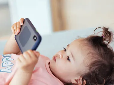 Photo of a toddler peering at the screen of a smartphone. Photo: GCShutter/E+ via Getty Images