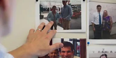 hand pointing at printed photos of David Fajgenbaum