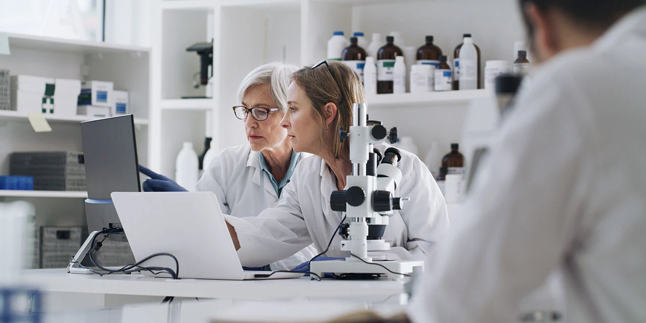 Photo depicting two women and a man working in a pharmaceutical laboratory (DMP/E+ via Getty Images)