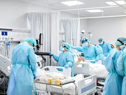 Photo depicting healthcare professionals with protective equipment caring for patients in a hospital setting. (Morsa Images/E+ via Getty Images)