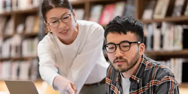 Professor talking to a student in a library