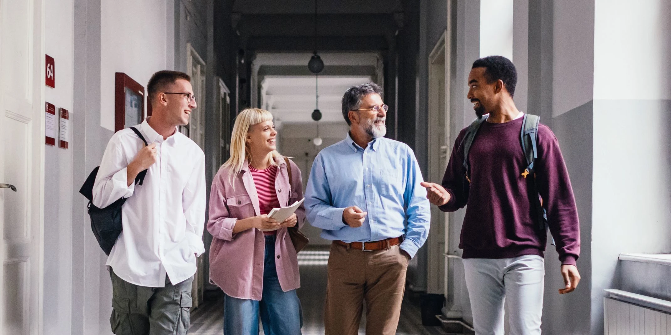 Group of college students and professor are walking and talking in a Academic university hallway