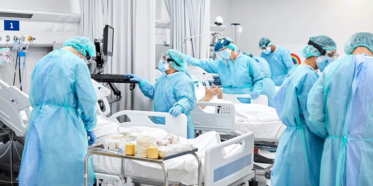 Photo depicting healthcare professionals with protective equipment caring for patients in a hospital setting. (Morsa Images/E+ via Getty Images)