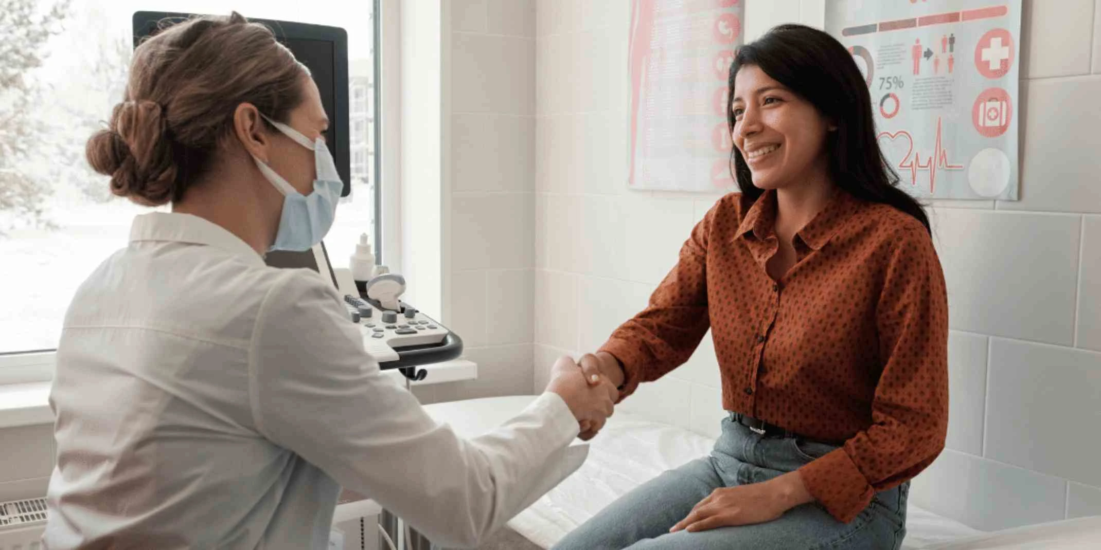 A masked white woman clinician shakes hands with her smiling female patient.