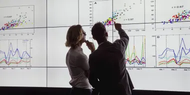 Woman and man analyzing data on a large screen (© istock.com/SolStock)