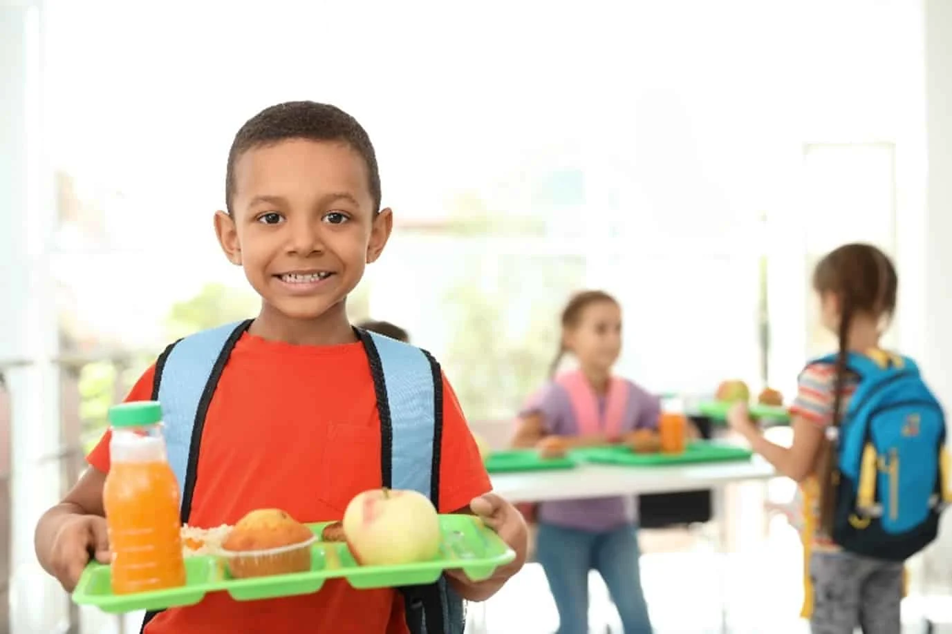 A kid holding a tray with his meal in school