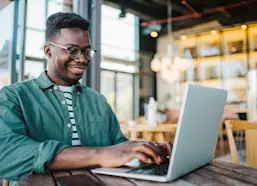 Male student sits on a laptop studying