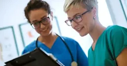 Two nurses looking at a patient record on a tablet.