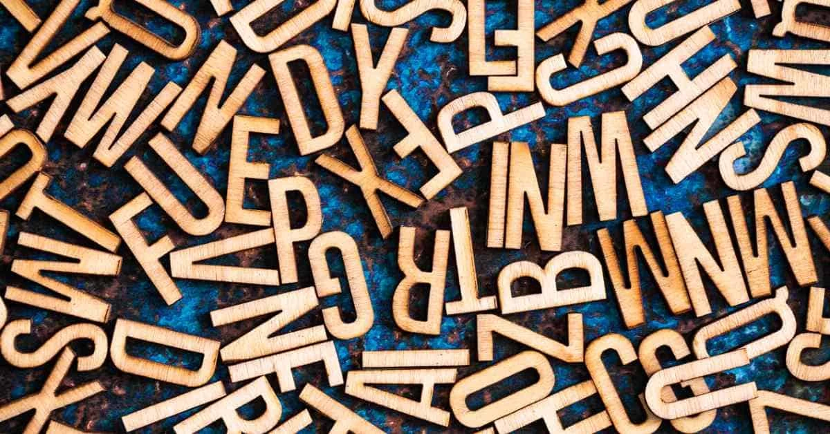 Wooden alphabet tiles scattered across metallic surface