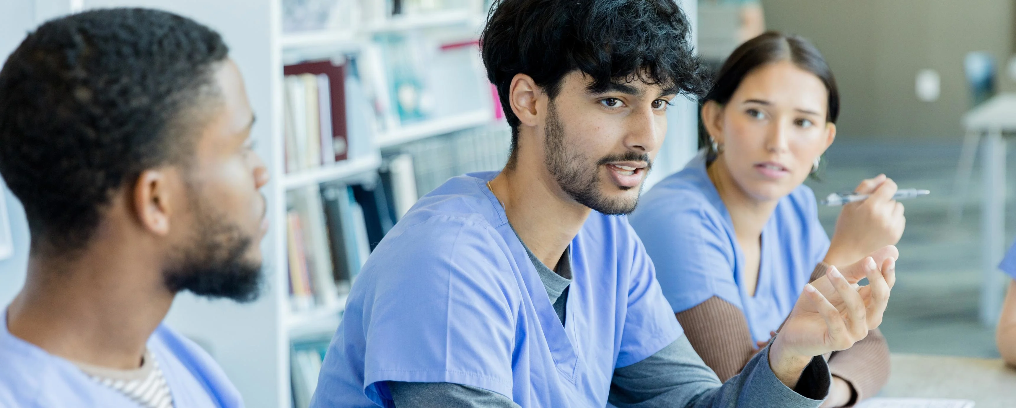 A diverse group of medical students meet at the library to discuss their project. GettyImages-1434510119.jpg