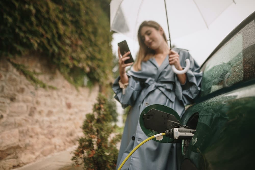 Lady in the rain charging her ev