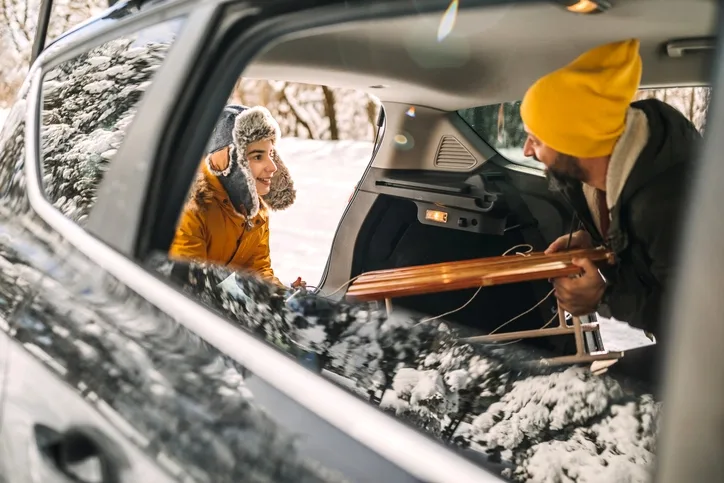 Father and son loading a sledge into an EV after playing in the snow