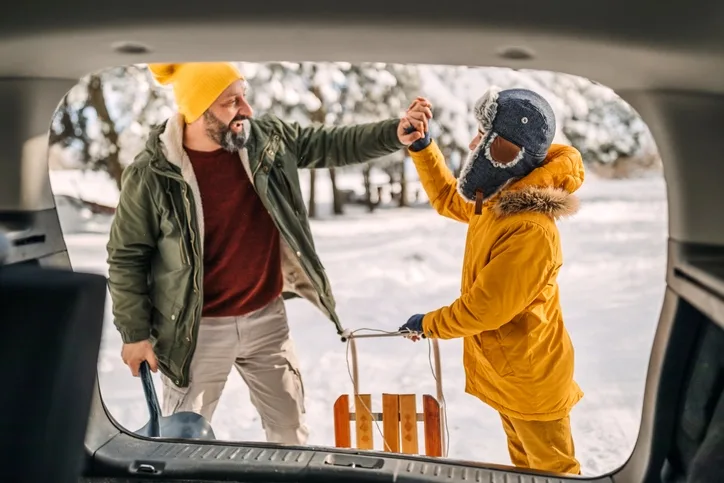 Father and son loading a sled into an EV 