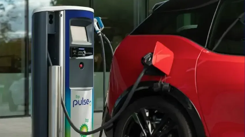 Red and black vehicle plugged into a bp pulse 50kW charger, located outside an office building.