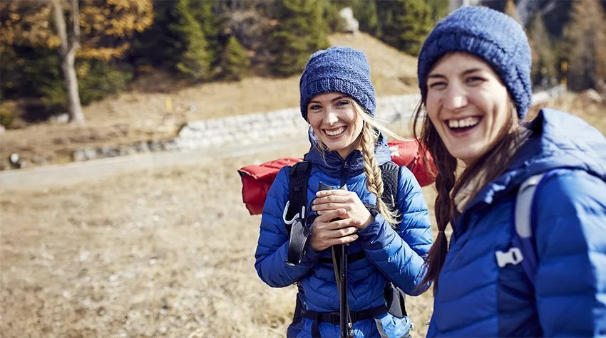 Two laughing young women hiking in the mountains.