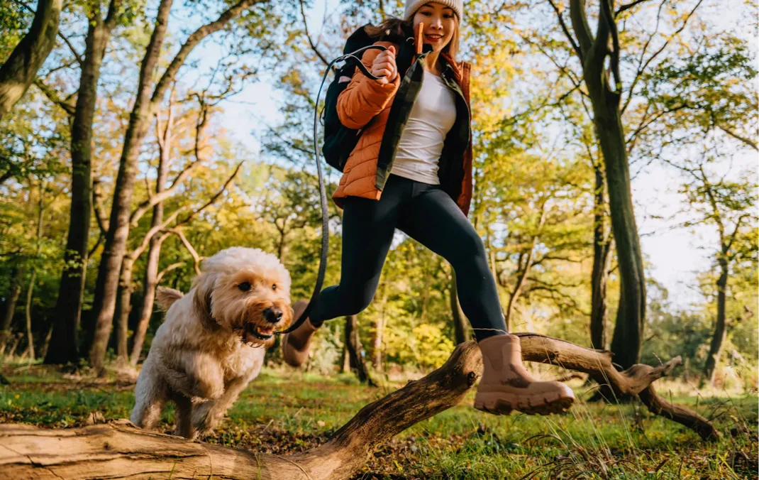 A woman hiking with her dog in the autumn season.