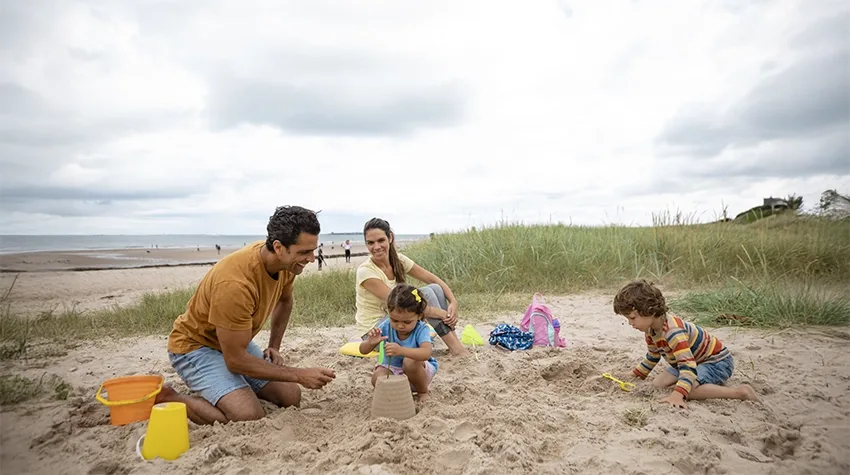 Two parents make sandcastles with their two children on the beach on a UK beach day