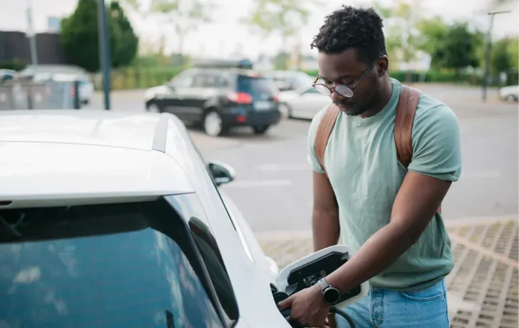 A man charging his white electric car.