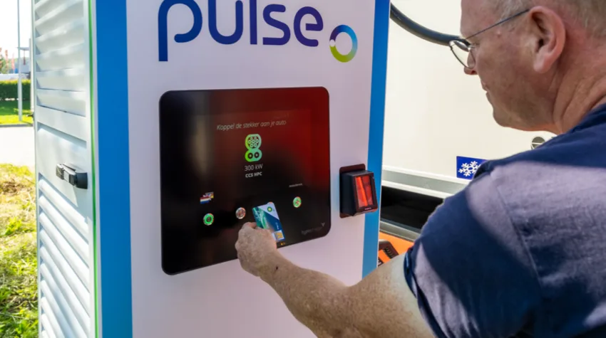 A man about to tap his RFID card on the bp pulse payment and charging machine. 