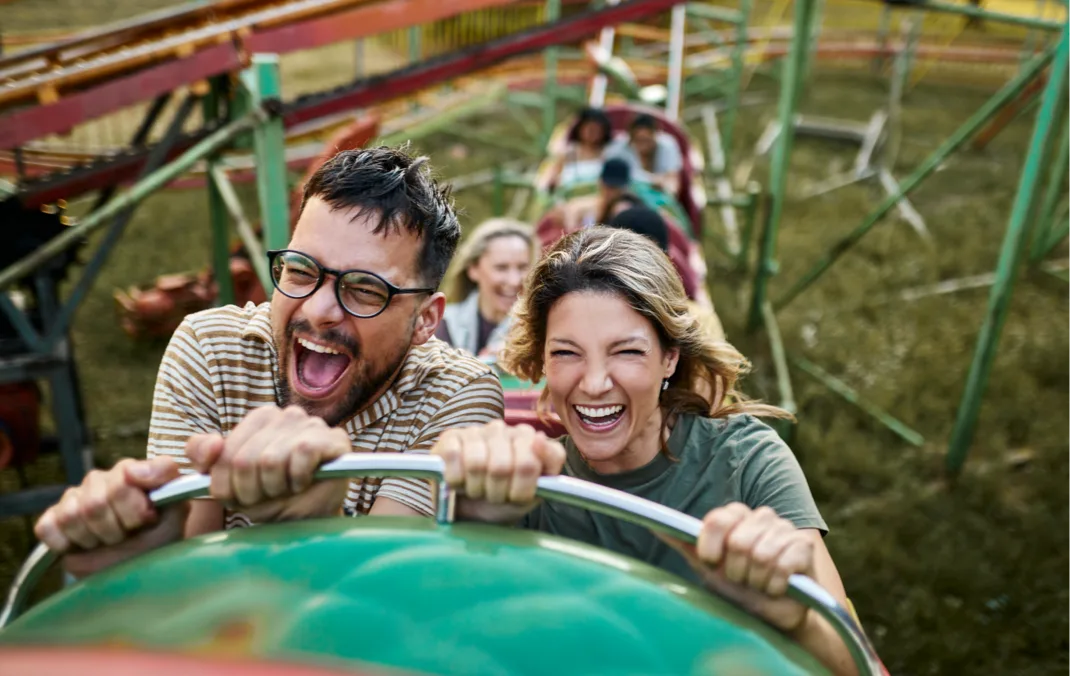 A family smiles as they go up a rollercoaster.