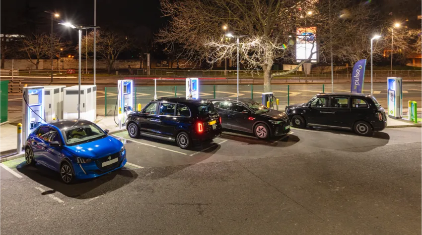 Four cars parked at a bp pulse charging station at night.