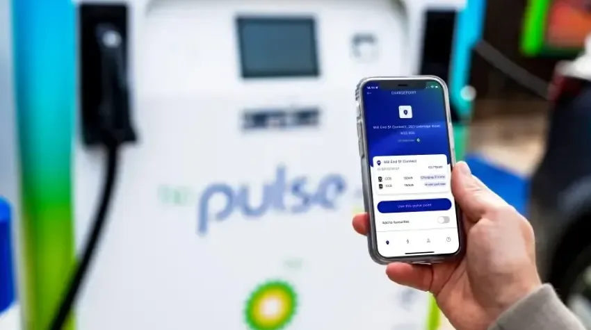 A hand holding a phone that displays some information about a bp pulse charging point.