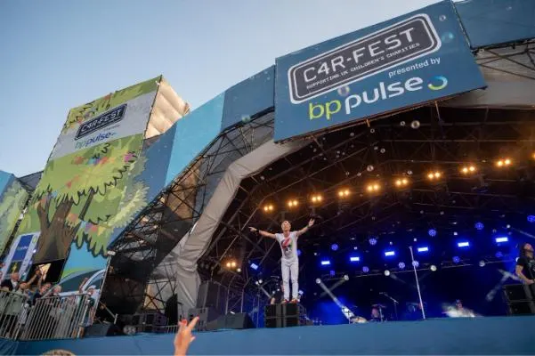 Person on stage at CarFest with a large bp pulse logo above the stage.