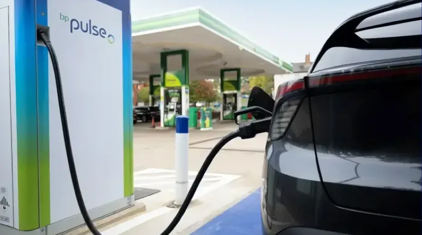 A black electric car is being charged at a bp pulse charging station.