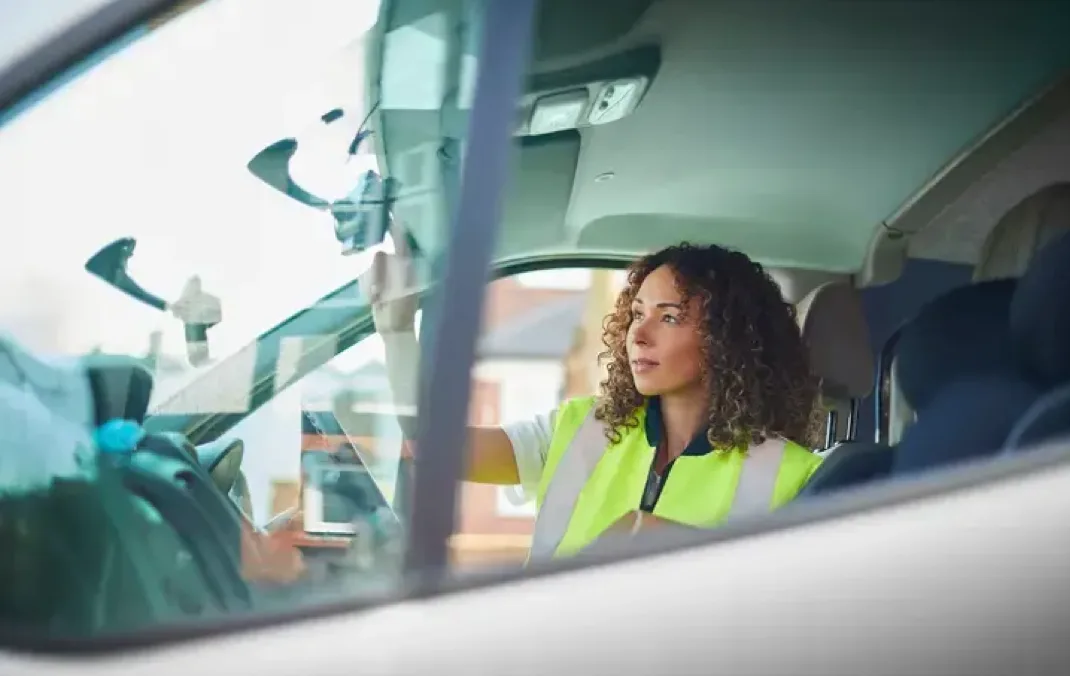 Lady wearing high visibility jacket in the driver seat of a van, entering a destination into the Sat Nav