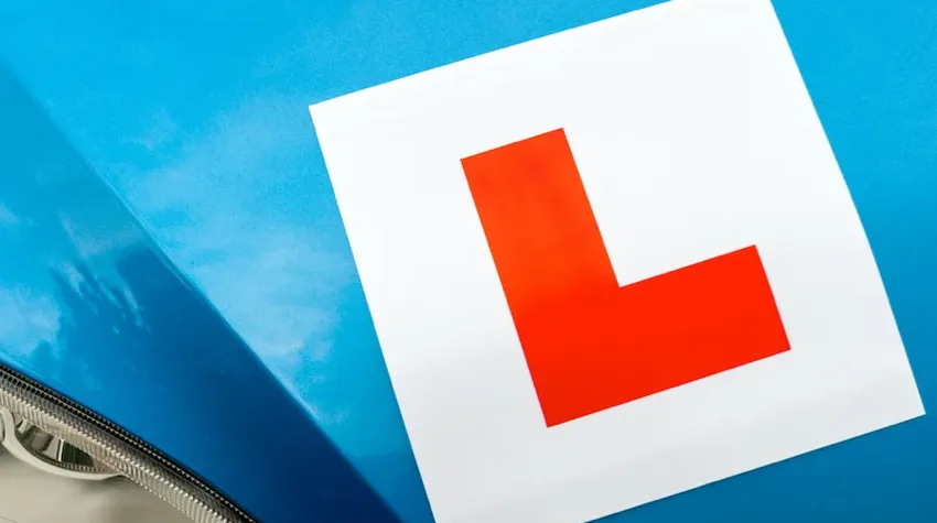 A red L (learner) plate is stick to a blue car. 
