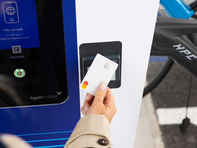 A close up of a woman tapping a payment card onto an Electric Vehicle charger.