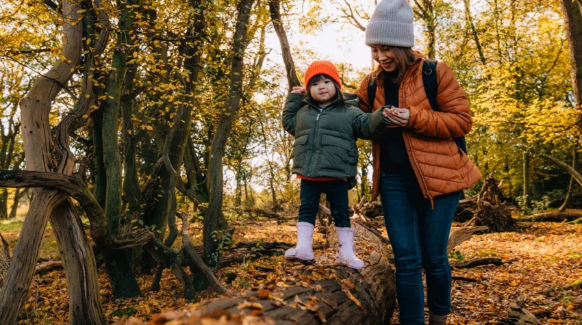 A woman hiking in the woods with her little daughter in the Autumn season.