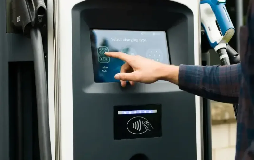 A person's hand touches the screen of a bp pulse charging station.