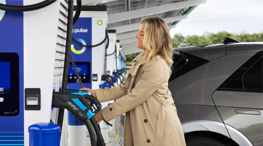 A woman charging her electric vehicle at a bp pulse charging station.