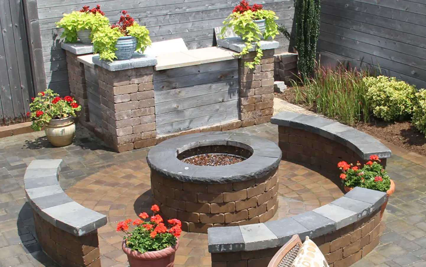 Newline Hardscapes -- Small Modern Garden Ideas With Plants: Ashland™ Fire Pit with benches and flower pots by Newline Hardscapes.