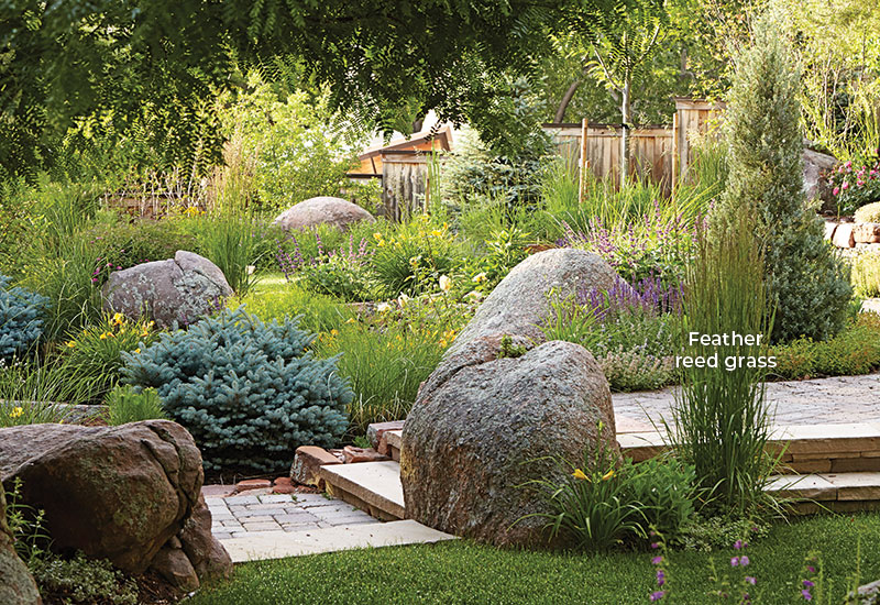 Adding-structure-to-your-garden-hardscaping-elements-label: The wooden fence along the back of the yard mimics the stairstepping path that leads visitors through this slightly sloped garden, tying the whole space together. 