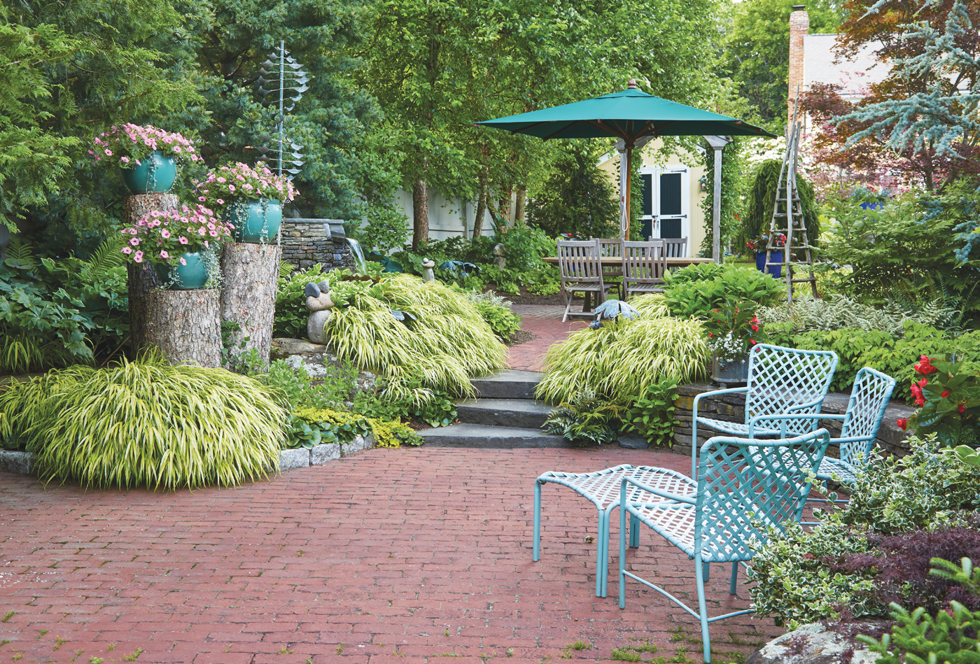 GG164 Joyce Hannaford shade patio with Hakonechloa: Instead of grinding out the old tree trunks, Joyce had them cut at different levels and uses them as posts for the containers to the left of the pathway.