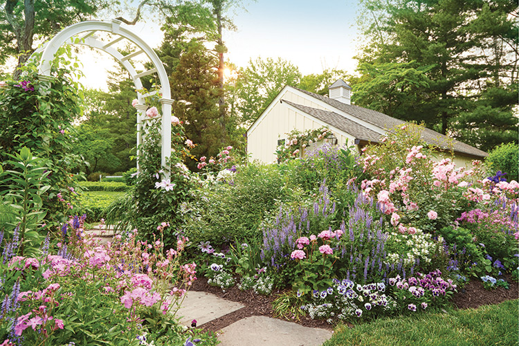 Heather Thomas Cape Cottage Garden in New Jersey: This white garden arbor makes a beautiful focal point along this color flower border in Heather Thomas' Cape Cottae Garden.
