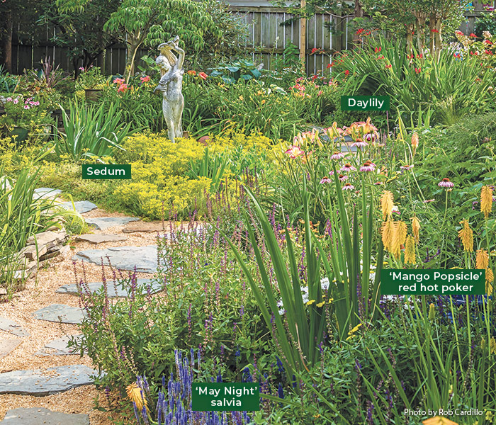 Statue in garden: Anne set slabs of natural stone in a thick layer of sand and filled in with pea gravel to create this walkway, which requires refreshing every few years. Spikes of orange red hot poker and blue salvia punctuate the view across the pollinator garden.