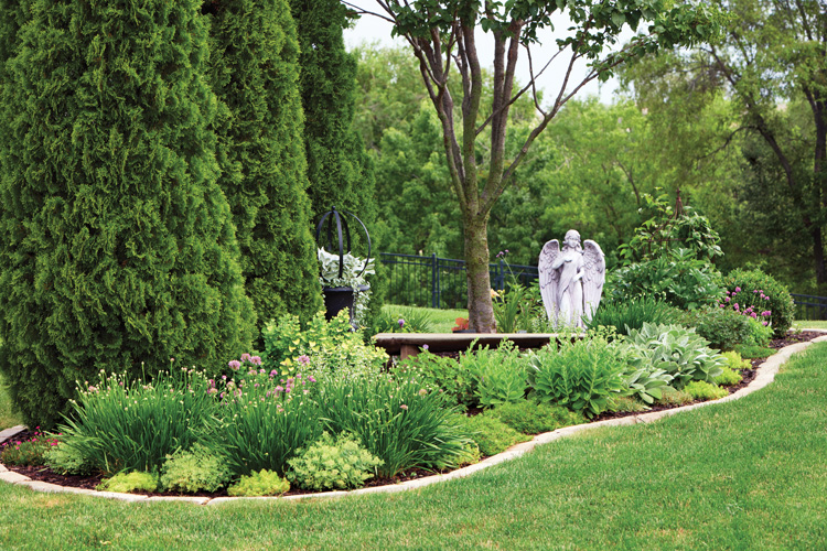 Ludlow island bed: This island bed lined with arborvitae is a special garden space with an angel statue and bench placed in memory of Joyce's father.