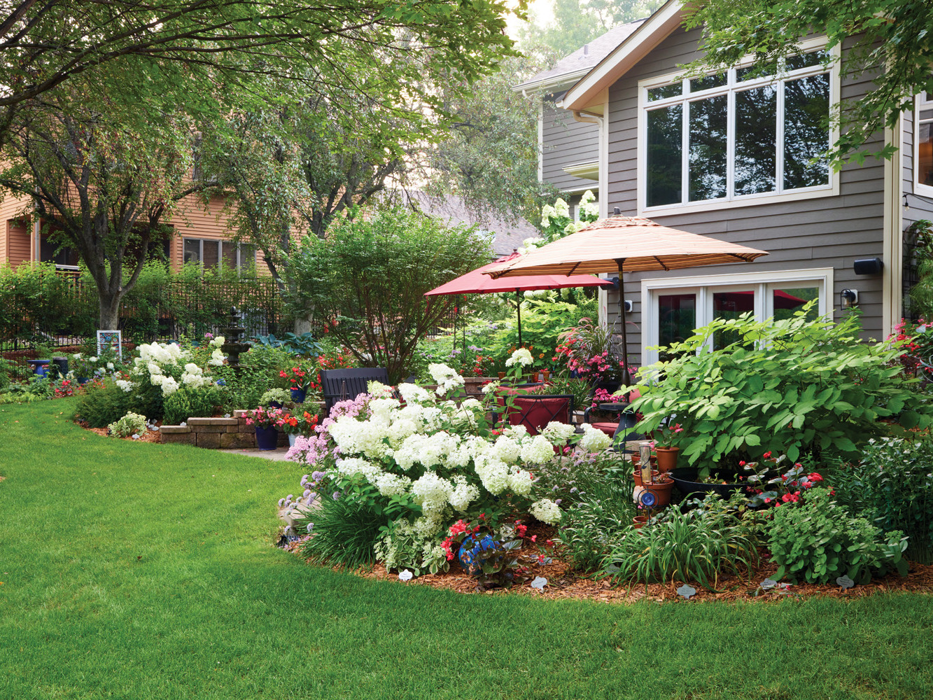 185 RGA Olson's backyard border with hydrangea: Sue thinks of her garden like a painting, stepping back from time to time to evaluate what it needs. When she sees a gap, she usually fills it in with plant divisions to keep the repetition strong.
